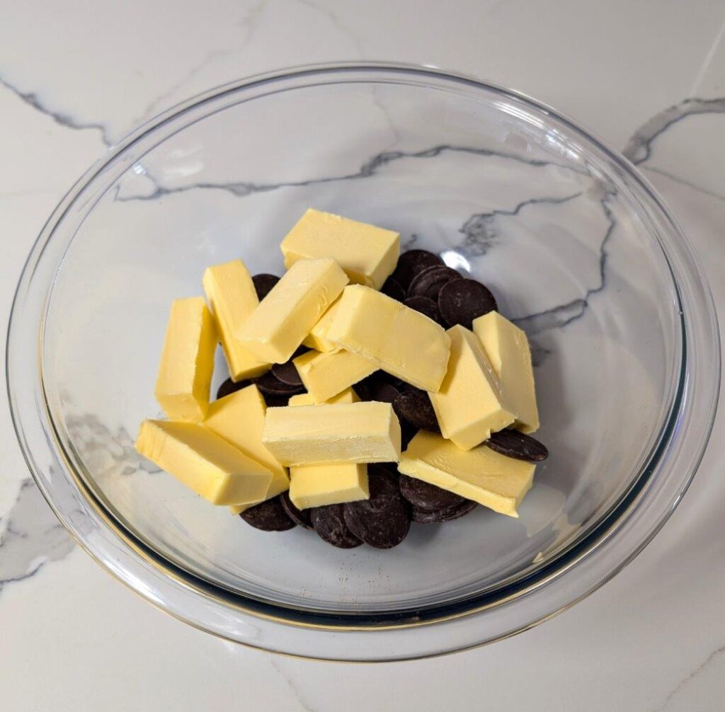 Dark chocolate pieces and cubed butter in a large glass bowl, ready to be melted