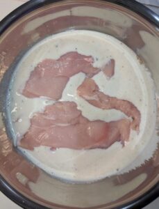 Chicken breasts in a large bowl with a buttermilk and herb marinade